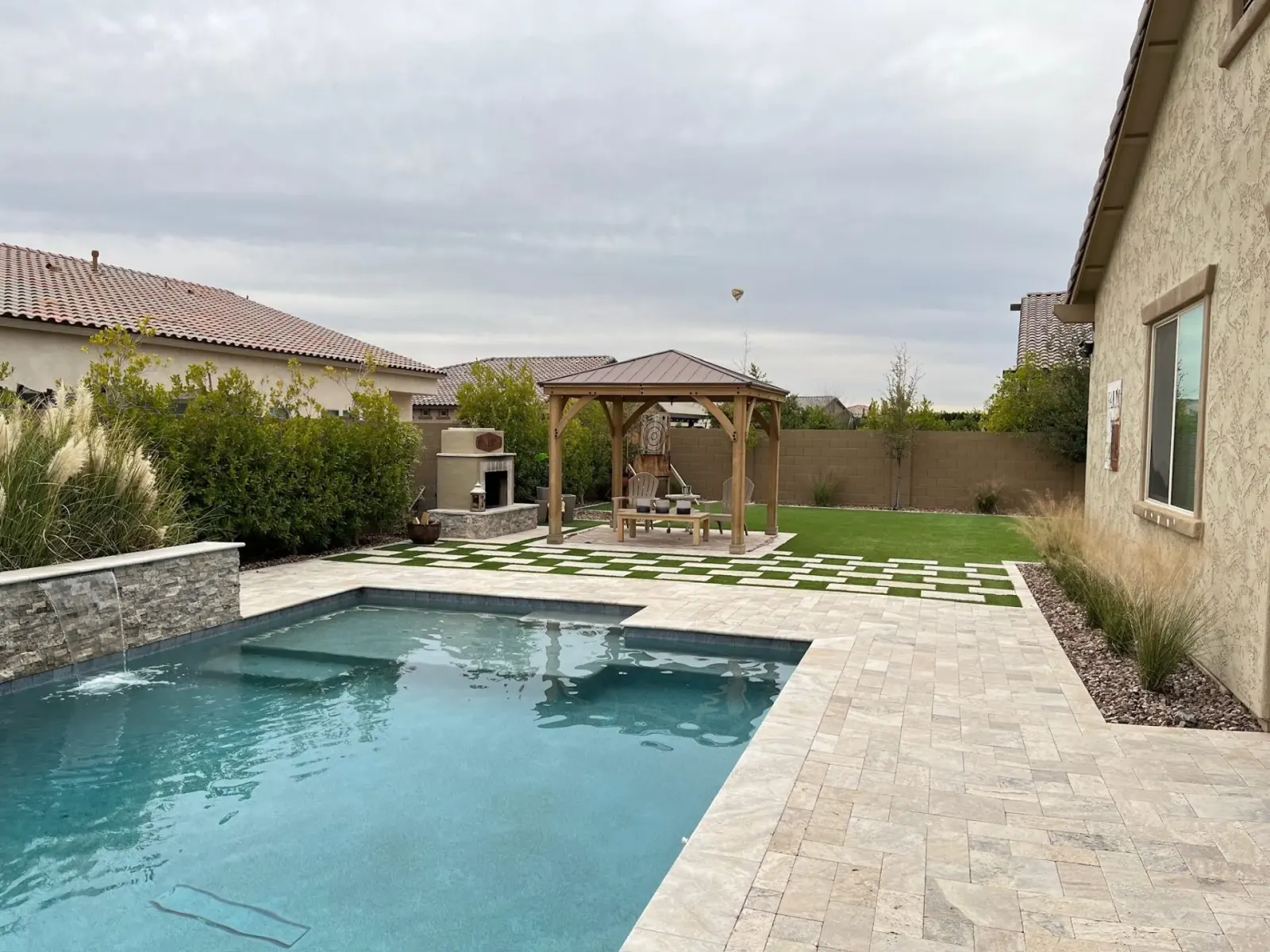 Geometric Pool, Raised Spa & Waterfalls, Travertine Decking in Goodyear, AZ — built by AE Outdoor Living