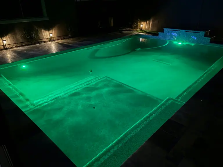 Pool and baja shelf illuminated in green at night.