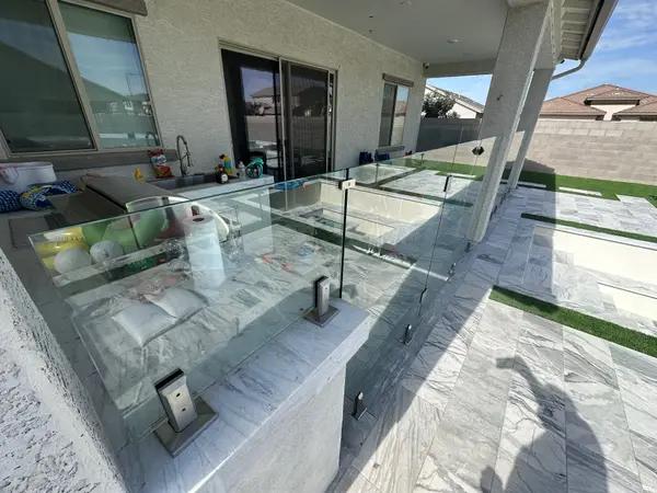 Close-up of frameless tempered glass panels and 316 marine-grade stainless spigot bases anchored into the pool deck.
