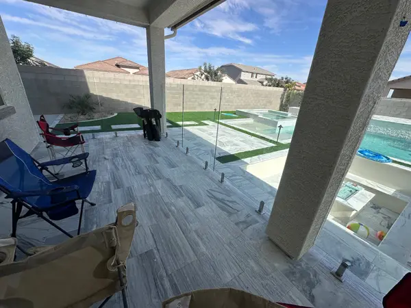 Frameless glass pool fence framing the pool view from a covered patio — clear sightlines to spa and water feature.