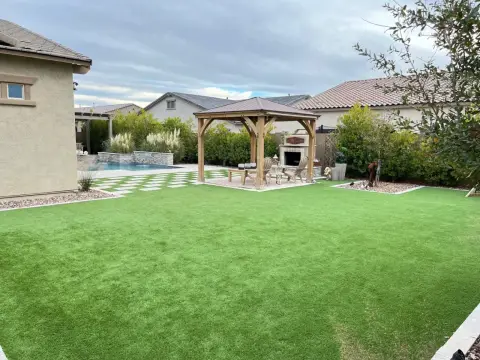 Wide backyard view showing turf paired with pool, gazebo, and pavers