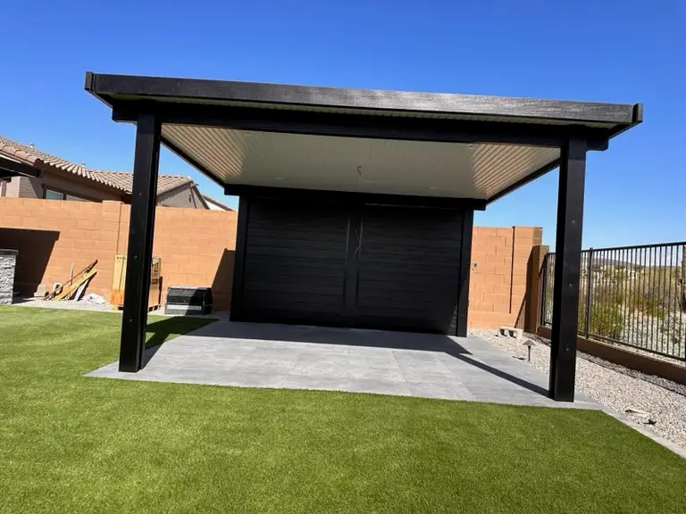 Freestanding blackout aluminum cover set on a porcelain paver pad with turf apron and privacy screen.